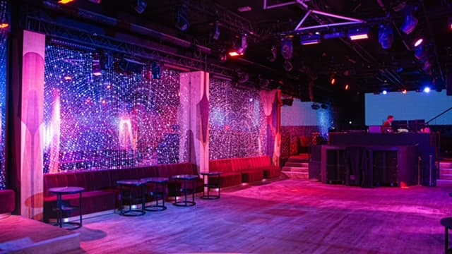 Salle de club avec espace lounge et cabine DJ.