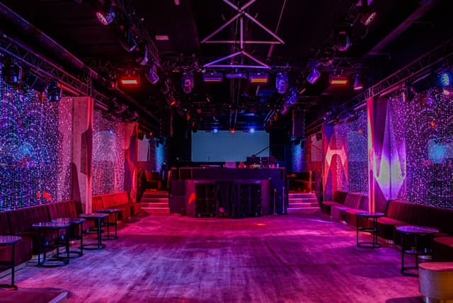 Salle de réception moderne avec piste de danse et scène DJ.
