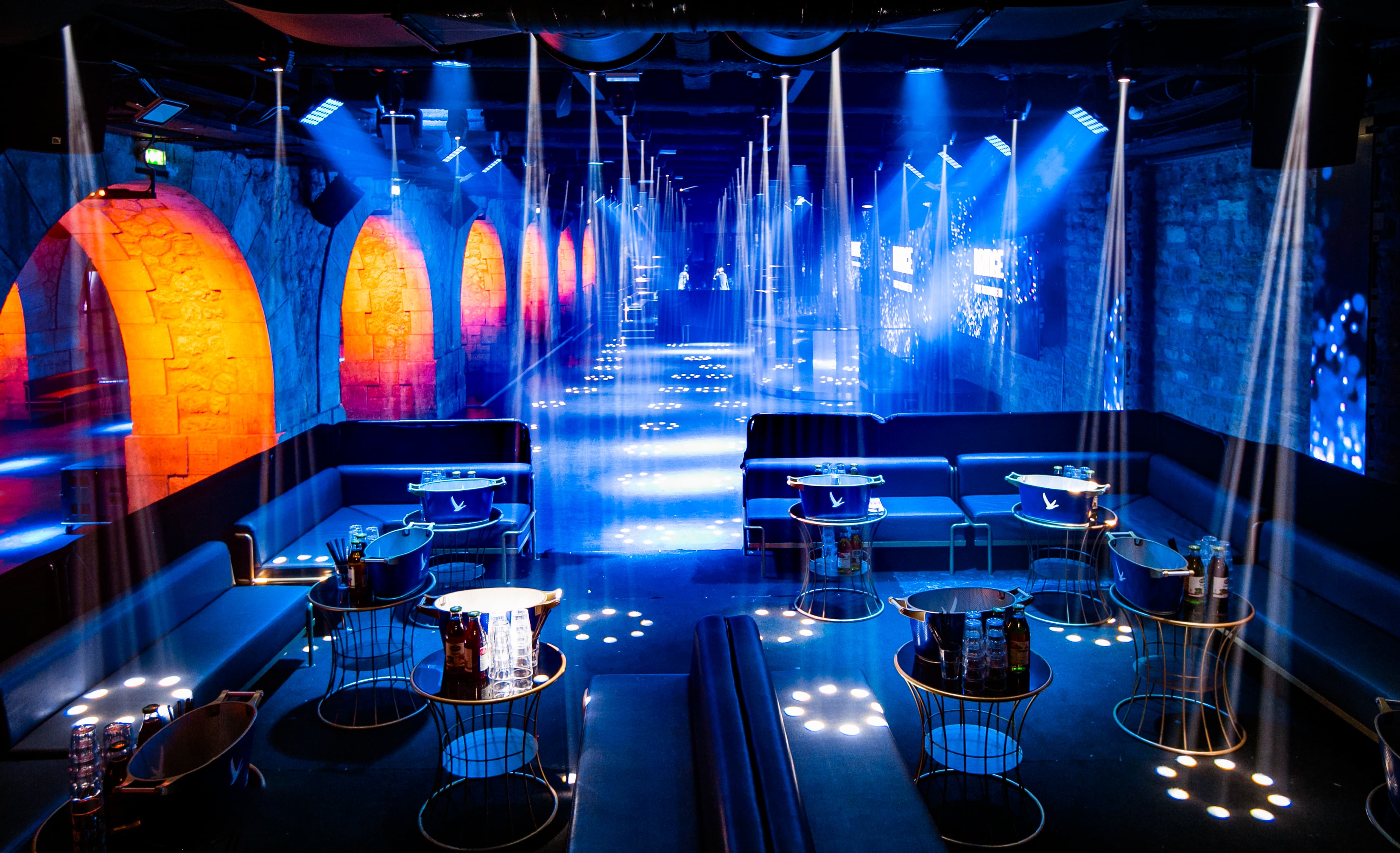 Salle dressee en tables rondes sous les arches, eclairage bleu
